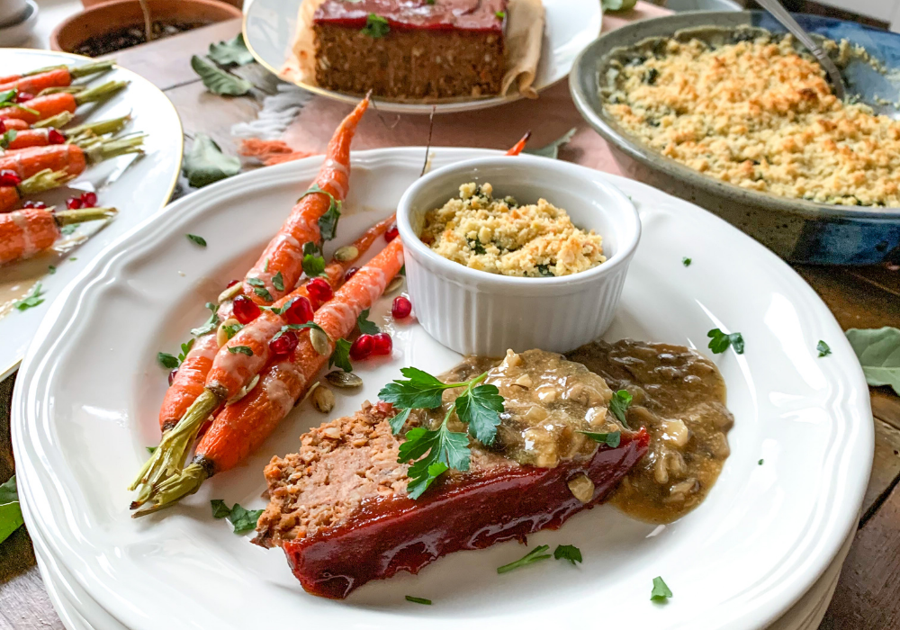 This image shows a slice of the best meatless meatloaf with mushroom gravy, roasted carrots, and kale gratin. All plant-based and gluten free.